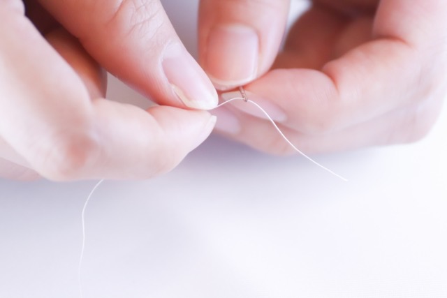 針に糸を通す手