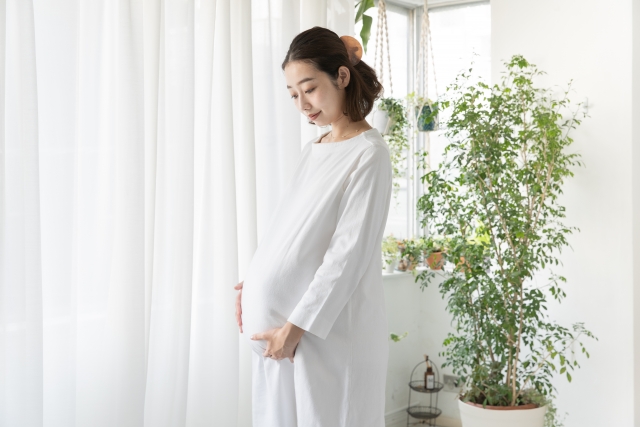 マタニティー　妊婦　お腹を抱える若い女性